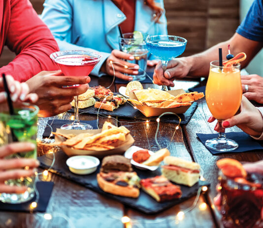 Group Of Friends Enjoying Appetizer Drinking And Eating In A Bar Close Up Of Hands Of Young People Holding Colorful Cocktails In The Happy Hour Time Social Gathering Party Time Concept