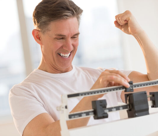 Excited Man Clenching Fist While Using Weight Scale